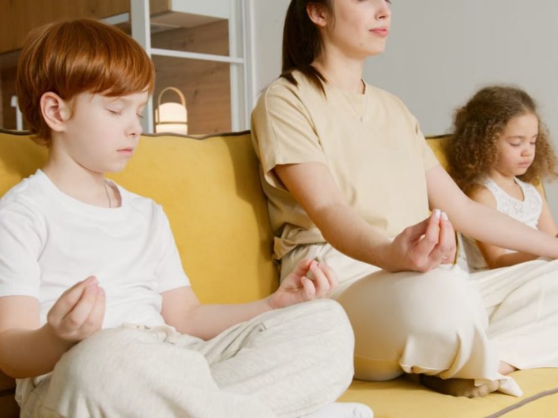 Family practicing meditation together on a couch, promoting mindfulness and relaxation.